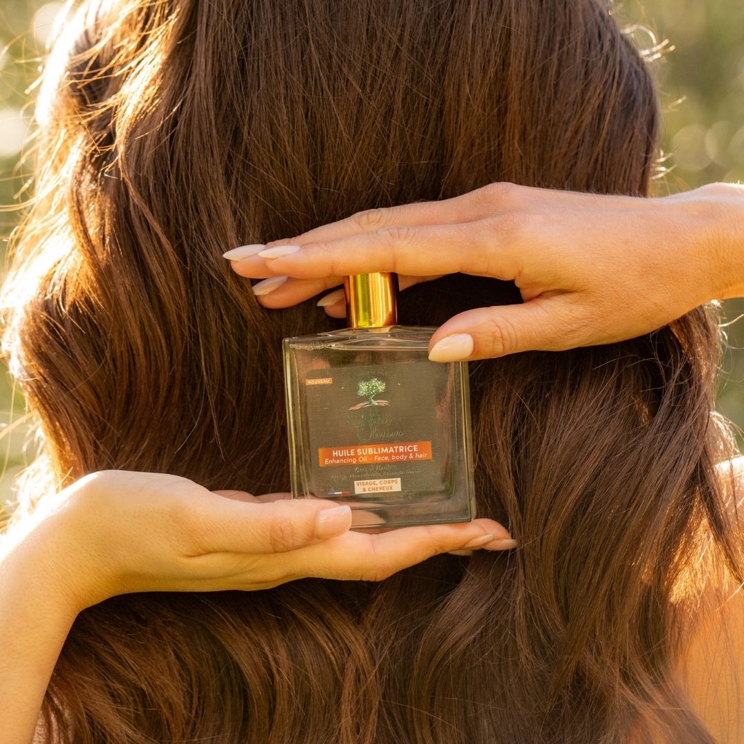femme tenant une huile d'argan sur ses cheveux longs bruns