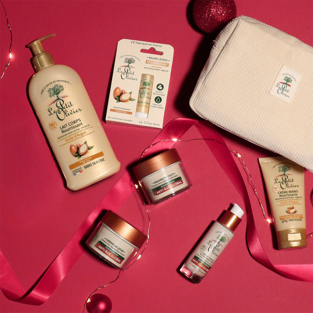 Trousse cosmétique beige avec produits visage et corps à l’huile d’argan, présentation sur ruban